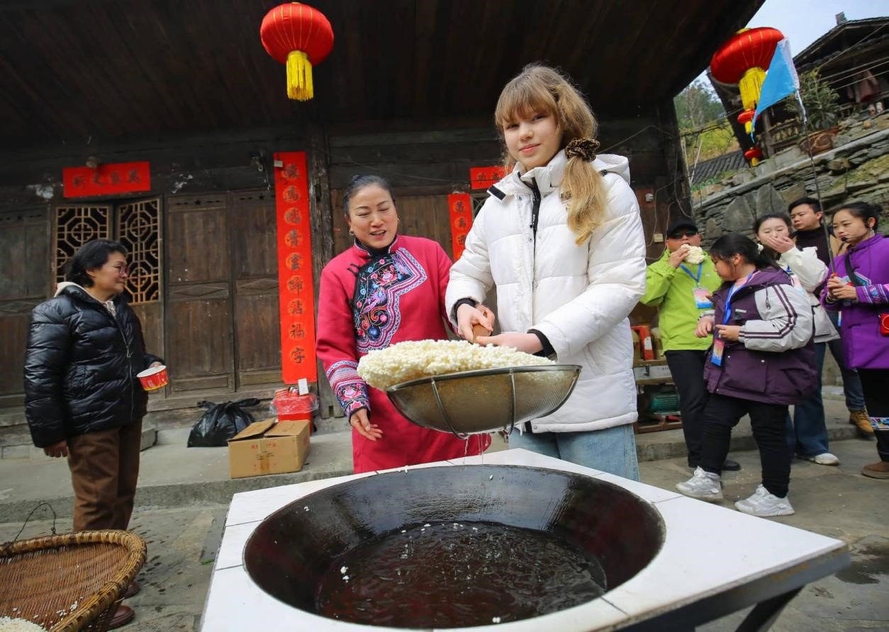 A scenic rural Chinese village with terraced fields and traditional homes attracting international travelers and online audiences.